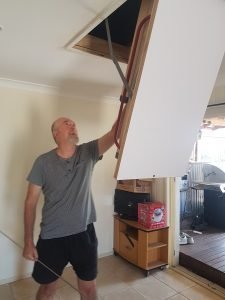 Man Folding Down Attic Ladder.