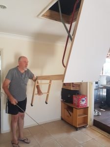 Man Folding Down Attic Ladder.