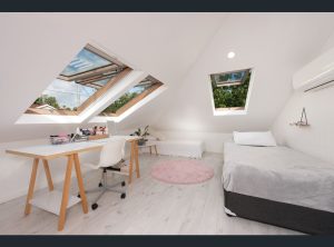 Fakro roof windows installed in attic bedroom with white interiors, study desk and bed visible